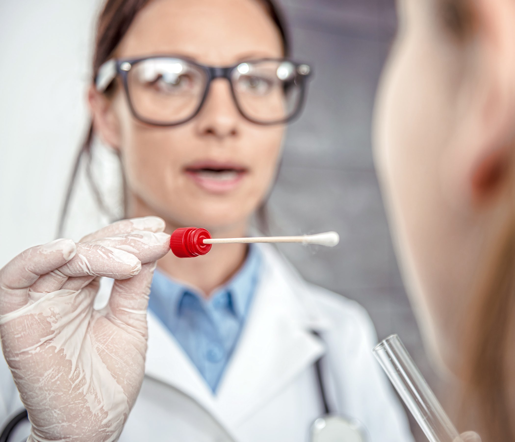 Pediatra femenino que usa una esponja para tomar una muestra de la garganta de un paciente
